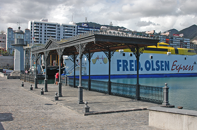 Marquesina y antiguo faro del puerto con ferry de transporte